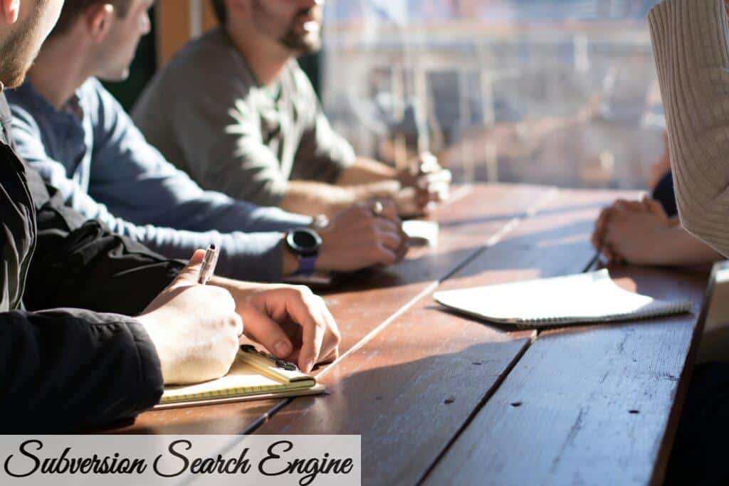 people sitting on chair in front of table while holding pens during daytime