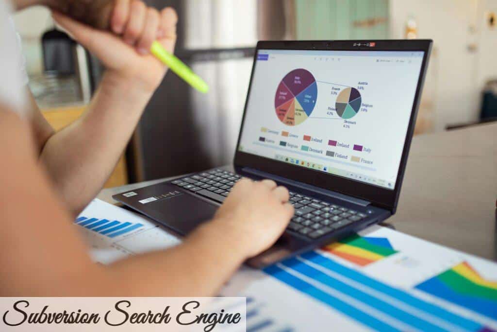 Person analyzing financial charts and graphs on a laptop with colorful documents, showcasing market analysis.