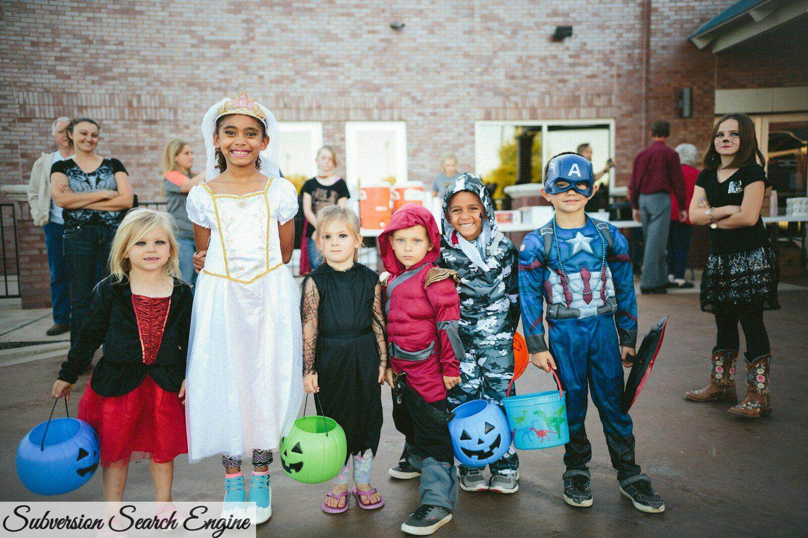 children standing while holding Jack 'o lantern and wearing costume