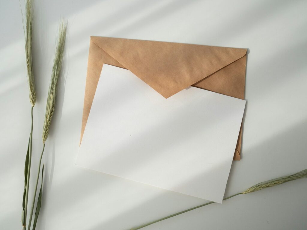 Hoja de papel blanca junto a un sobre marrón